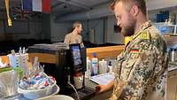 Ein Soldat bereitet einen Kaffee an einer Kaffeemaschine zu 