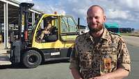 Portrait eines Soldaten, im Hintergrung ein Gabelstapler 