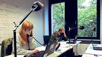 Eine zivile Beschäftigte der Bundeswehr sitzt im Büro des Gesundheitsamtes und arebitet mit Laptop und Telefon