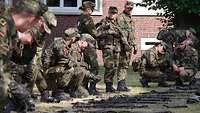 Soldaten schauen sich kniend ihre Waffen an.