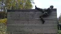 Ein Soldat hat einen Fuß am Rand der Holzwand eingehakt, bevor er sich über die Holzwand rollt.