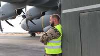 Ein Soldat lehnt am Tankwagen, der neben dem A400M steht, und schaut in die Ferne auf die Landebahn