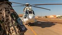 Ein Soldat steht auf einem Flugfeld, hinter ihm ein Hubschrauber