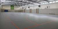 Blick in eine Sporthalle mit grauem Boden und Leuchtstoffröhren an der Decke