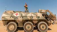 Eine Soldatin steht in der Wüste auf einem Transportpanzer Fuchs 