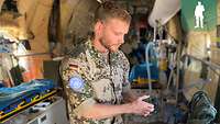 Ein Soldat steht in einem Flugzeugrumpf und hält ein Funkgerät in der Hand