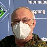 Ein Soldat und ein weiterer Mann stehen mit Muschutz und Abstand vor dem Liegenschaftplan des Krankenhauses