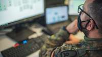 A soldier is sitting in front of a computer.