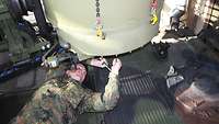 A soldier screwing something onto a metal container.