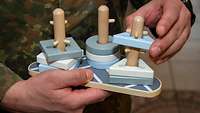 Ein Soldat hält ein Holzspielzeug in der Hand.