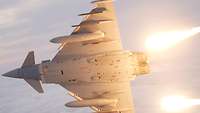 Ein nach rechts abdrehender Eurofighter stößt gleißend helle Flares (Täuschkörper) aus.
