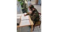 Ein Soldat sitz an einem Tisch und macht sich Notizen.