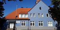 Ein blaues, zweistöckiges Gebäude mit einem großen, spitzen, roten Ziegeldach
