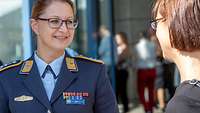 Lale Bartoschek, eine Soldatin in blauer Uniform, spricht mit einer jungen Frau.