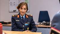 eine Frau in Uniform sitzt an einem Tisch