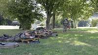 Soldaten liegen nebeneinander, jeweils neben ihnen ein aufgestelltes Gewehr.