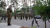 Ein Soldat steht vor einer Formation und befördert einen anderen Soldaten.