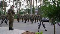 Ein Soldat steht vor einer Formation und befördert einen anderen Soldaten.