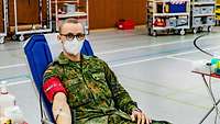 Ein Soldat liegt auf einer Liege und spendet Blut.