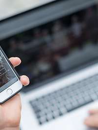 www.bmvg.de Die Website www.bmvg.de in einem Smartphone, im Hintergrund ein Notebook.