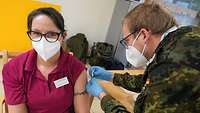 Ein Bundeswehr-Arzt impft eine Pflegefachkraft in einer Pflege- und Alte-neinrichtung.