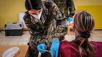 Eine Sanitätssoldatin impft eine Pflegefachkraft in einer Pflege- und Alte-neinrichtung.