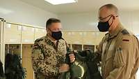 Ein Soldat übergibt eine Schutzweste an einen anderen Soldaten