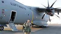 Ein Soldat steht mit Schutzweste und Rucksack vor dem Transportflugzeug A400M