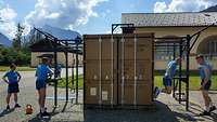 An einem Transportcontainer ist ein schwarzes Metallgestell angebracht, an dem Soldaten trainieren.