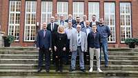 Die Ausbilder stehen bei einem Gruppenfoto auf einer Treppe.