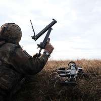 Ein Soldat liegt mit einer Waffe in einer Stellung