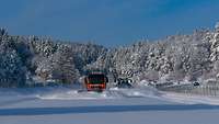 Zwei Schneepflug-Kraftfahrzeuge räumen Straßen und Plätze im Gebirge frei.