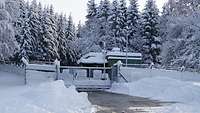 Zugeschneite Haupteinfahrt einer Bundeswehr-Dienststelle mitten im schneebedeckten Wald.