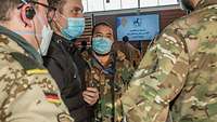Drei Soldaten und ein Zivilist, alle mit Mund-Nasen-Schutz, stehen im Kreis und reden miteinander