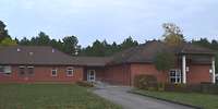 Zwei große mit einem Mittelteil verbundene Flachbungalows, mit roter Ziegelfassade