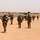 Bundeswehr soldiers with weapons and blue UN caps on patrol in a desert landscape