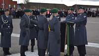 Sechs Soldaten haben eine Hand auf die Truppenfahne gelegt, die von einem Soldaten gehalten wird.