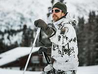 Ein Soldat in Schneetarnuniform steht auf Skiern am verschneiten Waldhang der bayerischen Reiteralpe.