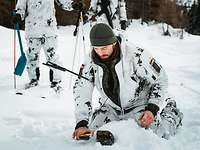 Ein Soldat in Schneetarnuniform fährt mit einem Lawinensuchgerät über den Schnee.