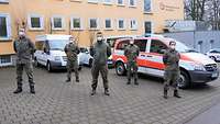 Soldatinnen und Soldaten stehen vor Einsatzfahrzeugen des Deutschen Roten Kreuzes, die vor dem DRK-Bildungszentrum parken.