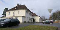 Ein helles zweigeschossiges, quadratisches Haus mit zwei Anbauten