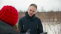 Direktor WTD 91 Frank Dosquet mit Journalistin Männliche Person gibt weiblicher Person Erläuterungen in schneebedecktem Gelände