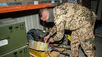 Ein Soldat legt ein kleines weißes Plastikröhrchen in einen Karton in der Lagerhalle