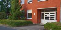 Teilansicht eines mit roten Backsteinen verkleideten Hauses mit einem breiten Eingang