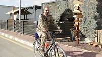 Ein Soldat sitzt auf einem schwarzen Fahrrad. Auf dem Gepäckträger ist ein Blaulicht montiert