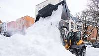 Ein Bagger kippt eine große Menge Schnee aus