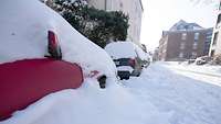 Eine Schneebedeckte Straße mit eingeschneiten Fahrzeugen