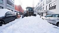 Ein Bagger schiebt große Schneemengen vor sich her