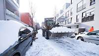 Ein Bagger auf einer Straße mit der Schaufel voll Schnee