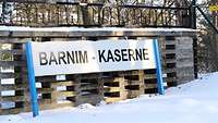 An der Einfahrt einer Bundeswehr-Liegenschaft hängt ein Schild am Zaun: "Barnim-Kaserne"